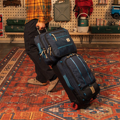 General model shot of Global Travel Bag 30L in "Navy" slipped over the handle of the Global Travel Bag Roller