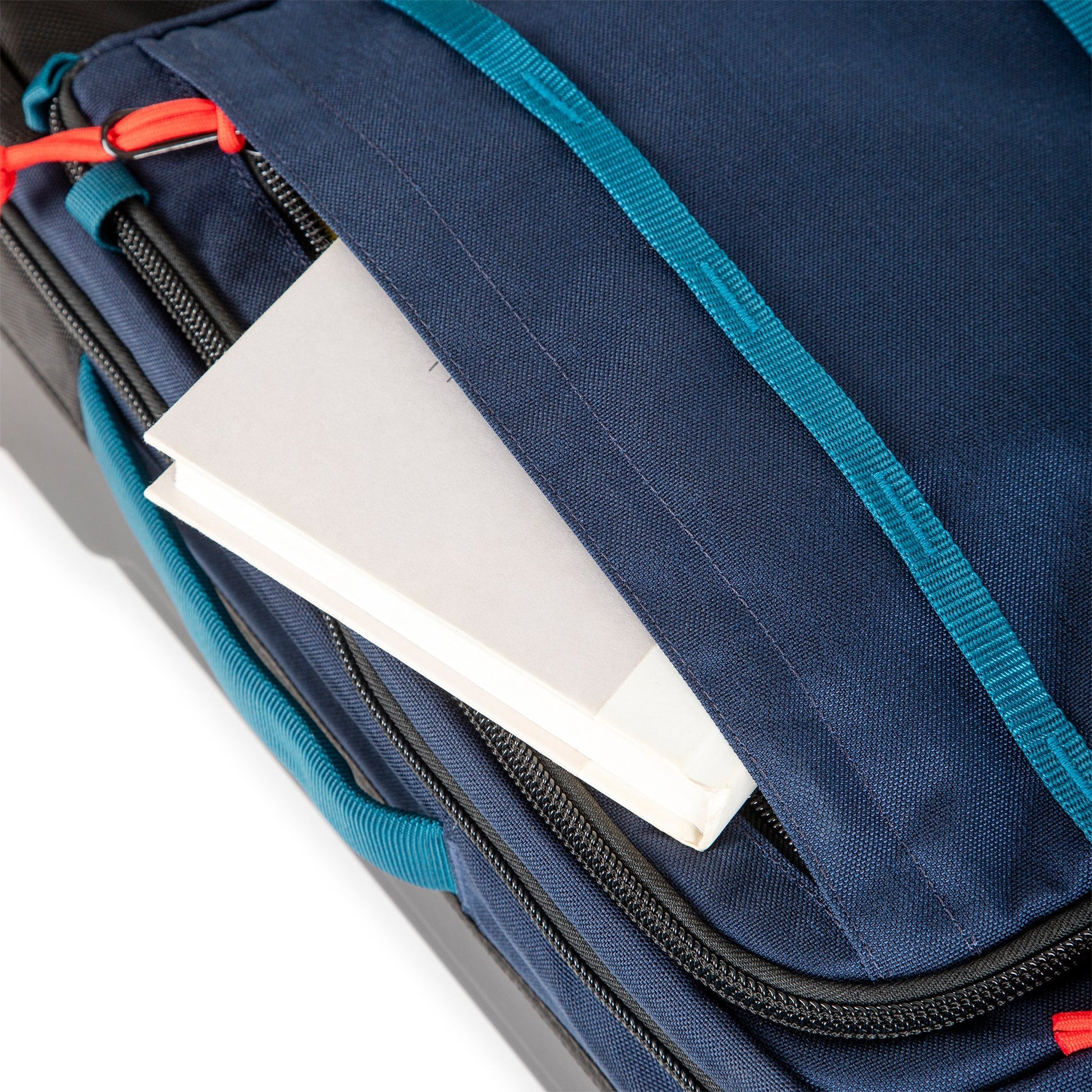 General shot of front zipper pocket on Topo Designs Global Travel Bag Roller durable carry-on convertible laptop rolling backpack suitcase in Navy blue.