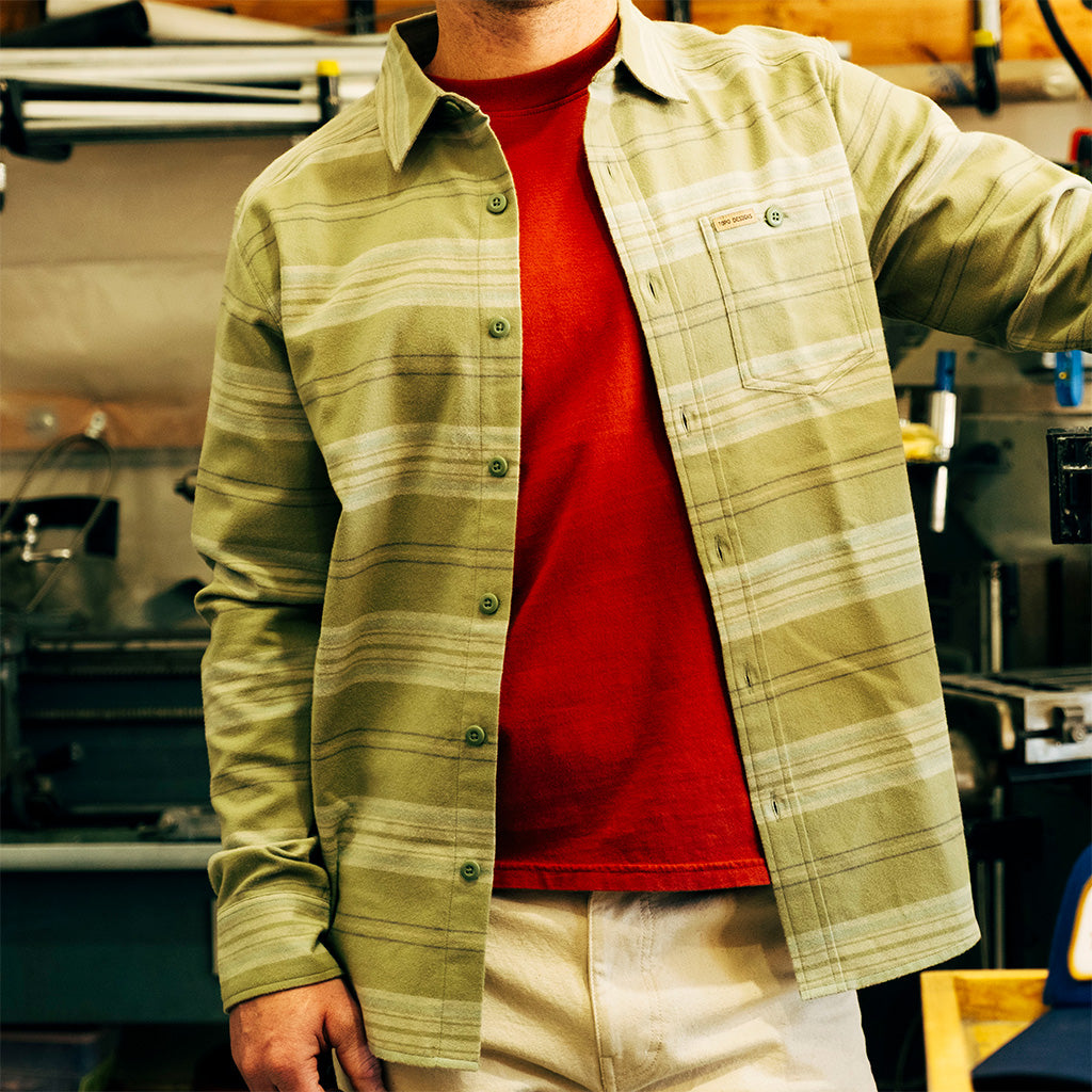 General lifestyle image of person wearing an "Oil Green Horizontal Stripe" Mountain Shirt Lightweight over a red shirt in an indoor setting