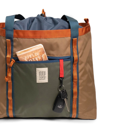 General front view of Topo Designs Mountain Utility Tote in "Olive / Dark Khaki" with notebook and keys.